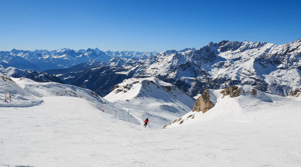 Skier in a red jacket skiing the pista da sci a Cervinia near Valtournenche